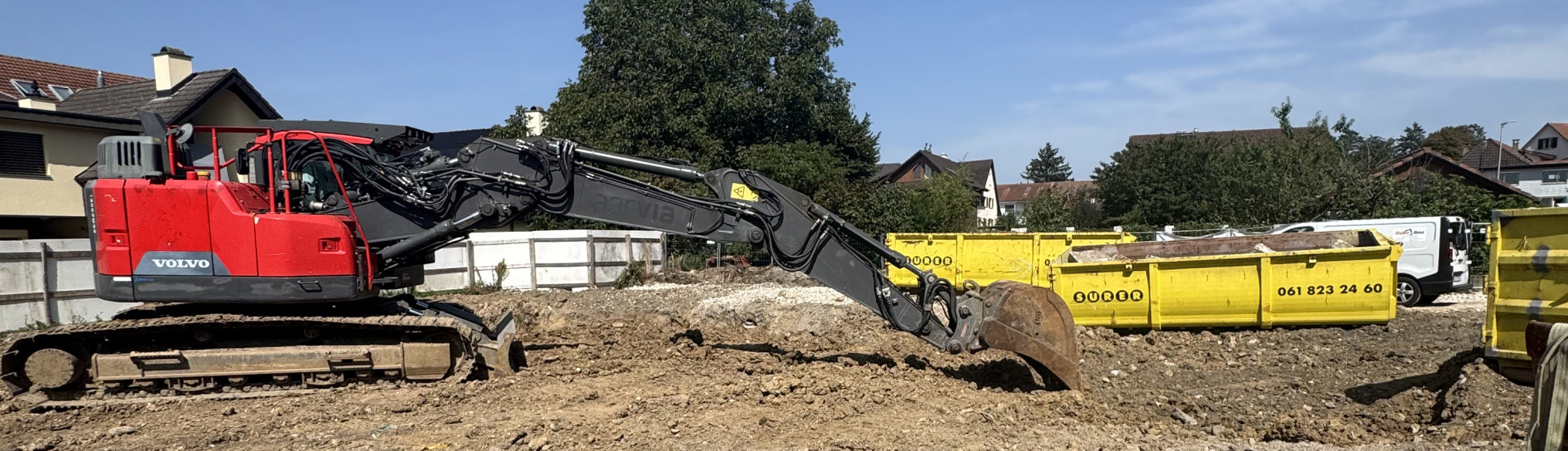 Abbruchbagger und gelbe Mulden auf einem geräumten Grundstück