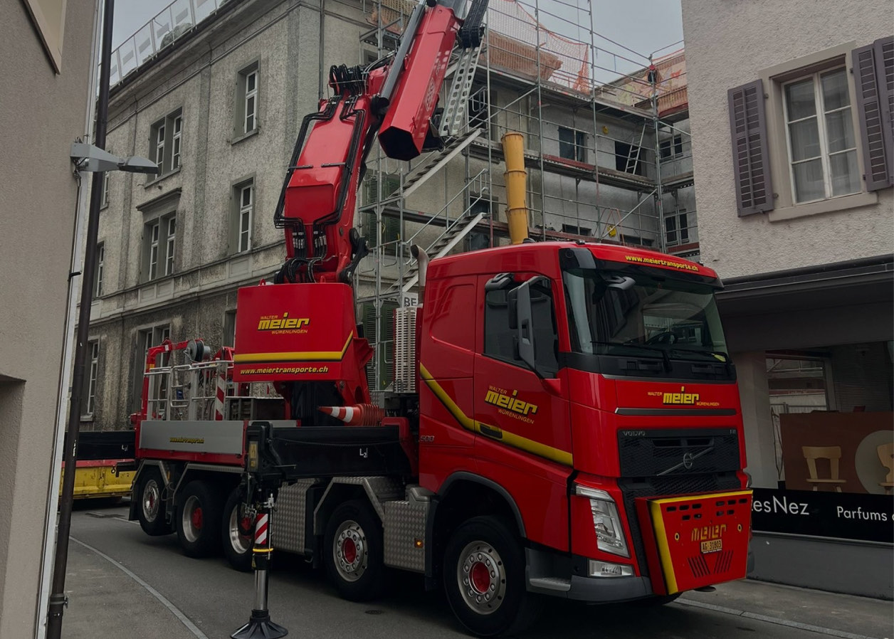 Roter Kranwagen vor einem eingerüsteten Altbau